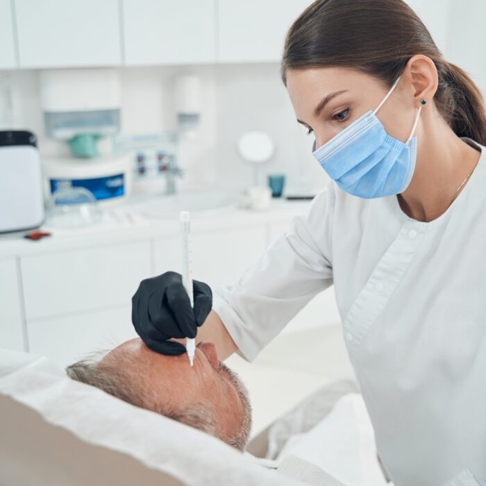 Cosmetologist performing cleansing skincare procedure in clinic