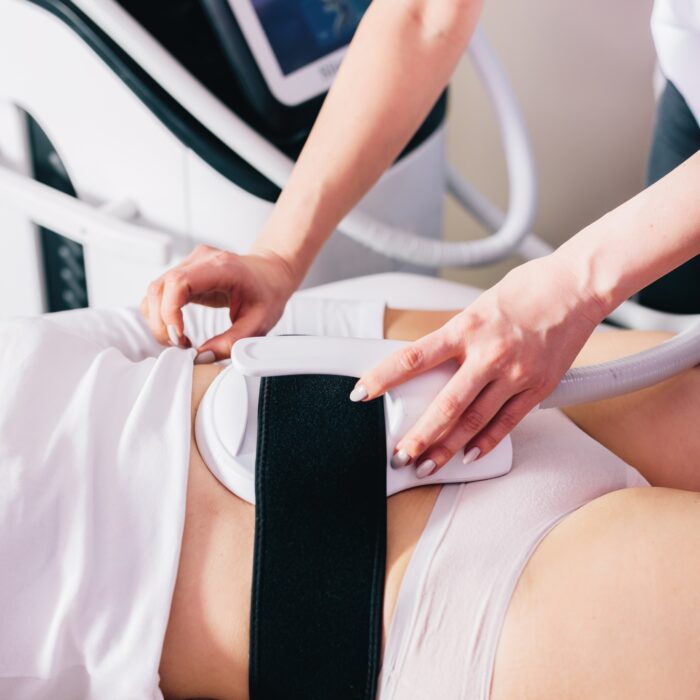 Woman getting ems treatment on abdomen to burn fat and build muscles