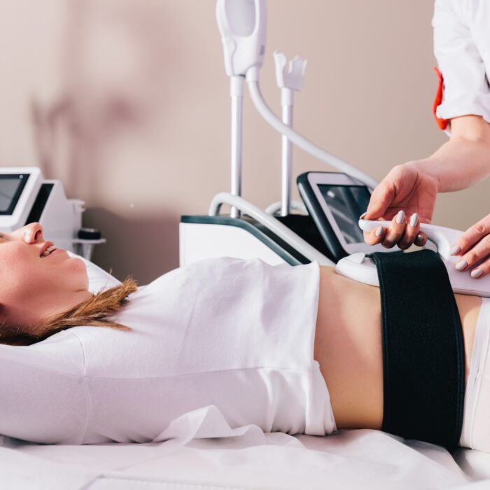 Woman getting ems treatment on abdomen to burn fat and build muscles