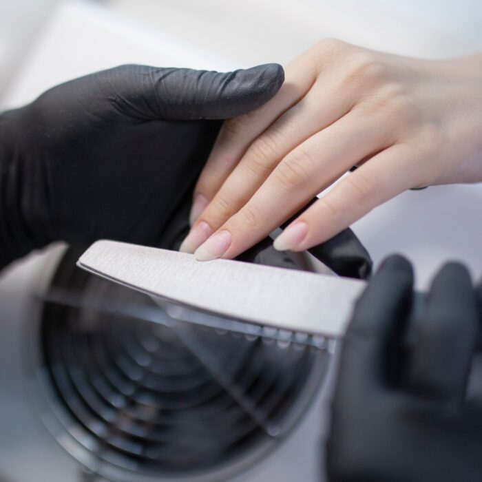 a Manicure treatment at nail salon, master working and doing manicure with nail file